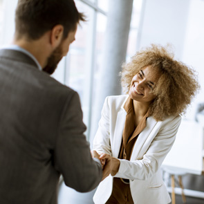 Two business people shake hands and greet each other.