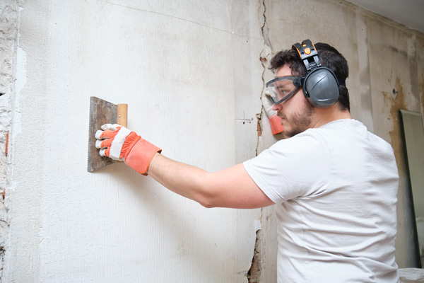 A construction worker completes repairs to the exterior of a home.