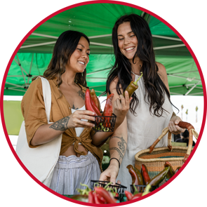 A couple friends checkout produce at a local farmer's market.
